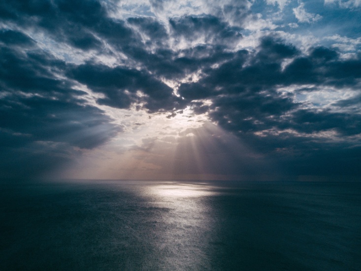 sun shining through clouds over the sea