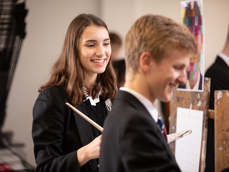 girl smiling with a paint brush at school