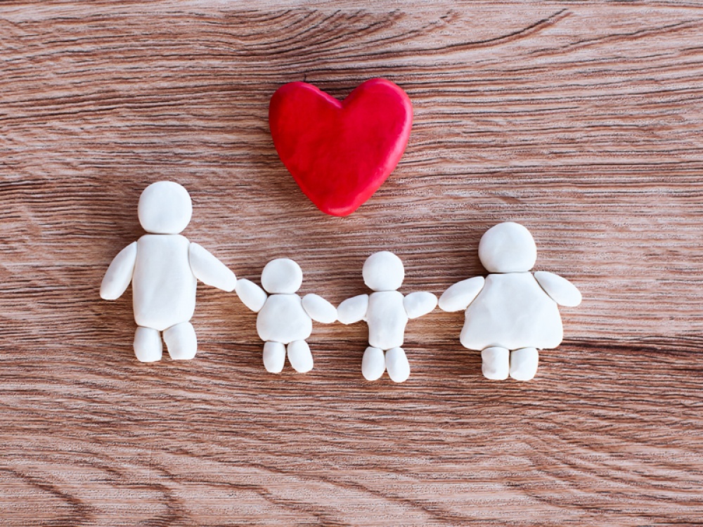 clay people with red clay heart on a wood background
