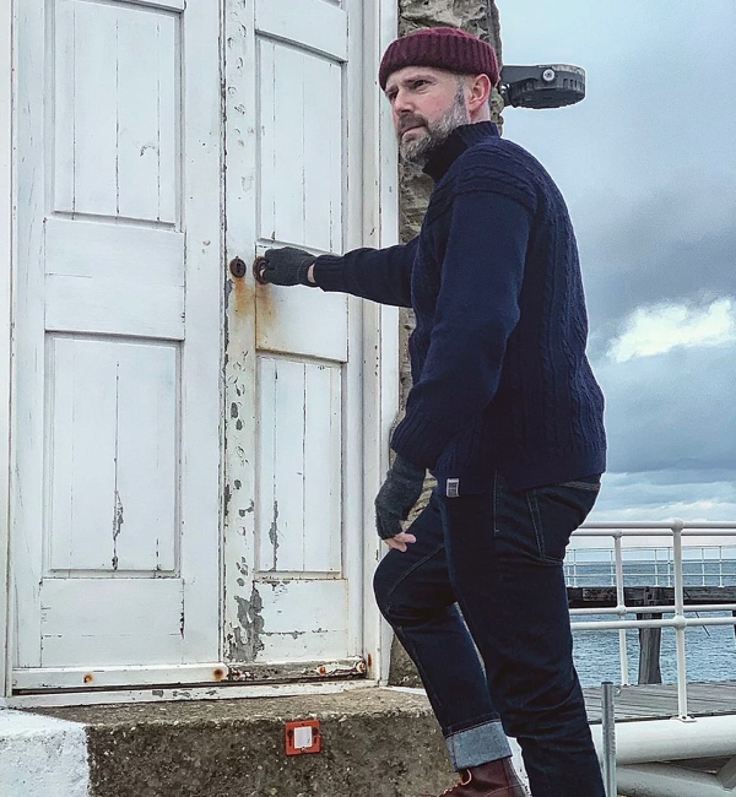Man opening old wooden door wearing jumper and beanie hat