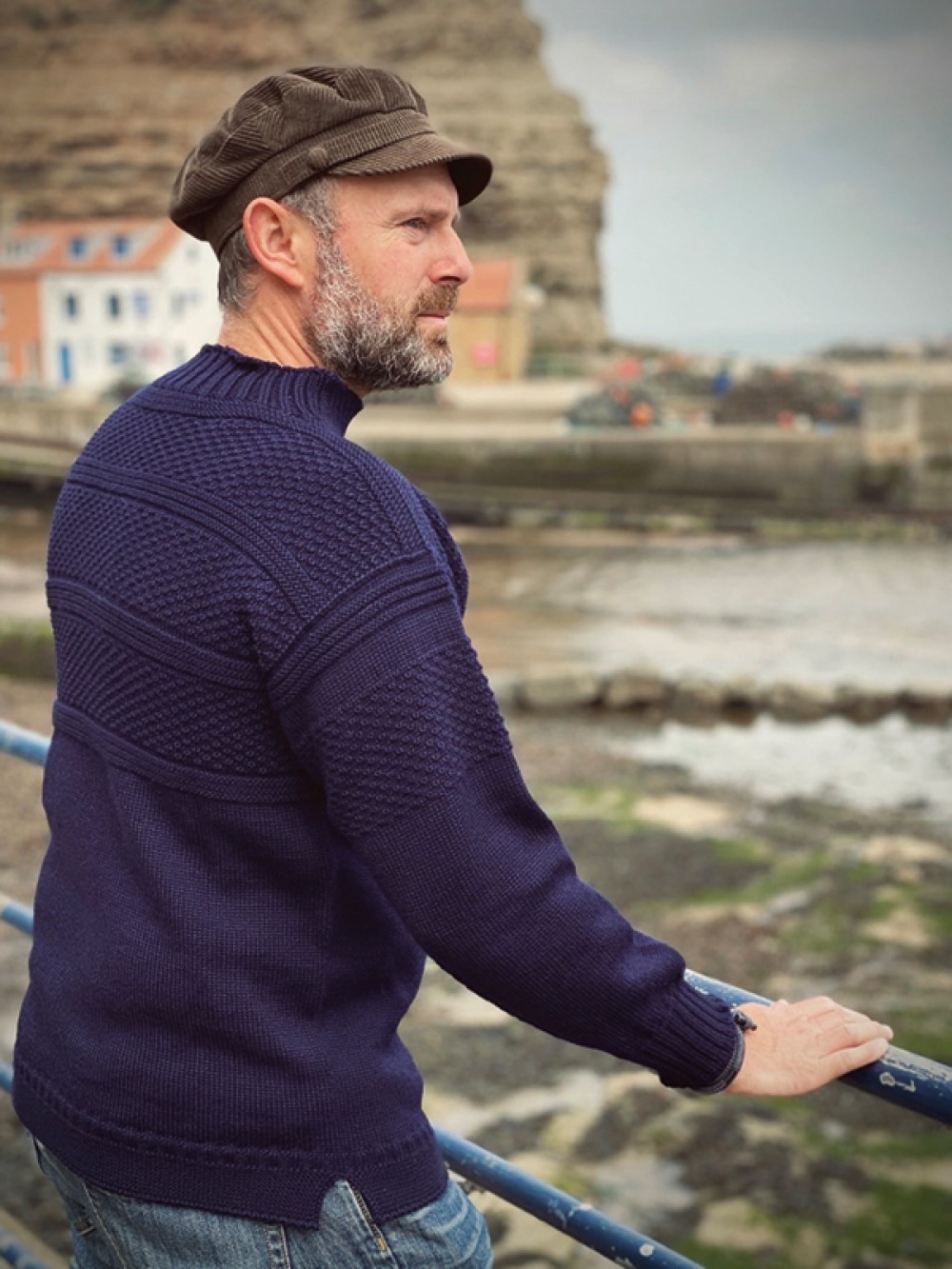 Matthew Pugh wearing jumper and hat looking out to sea