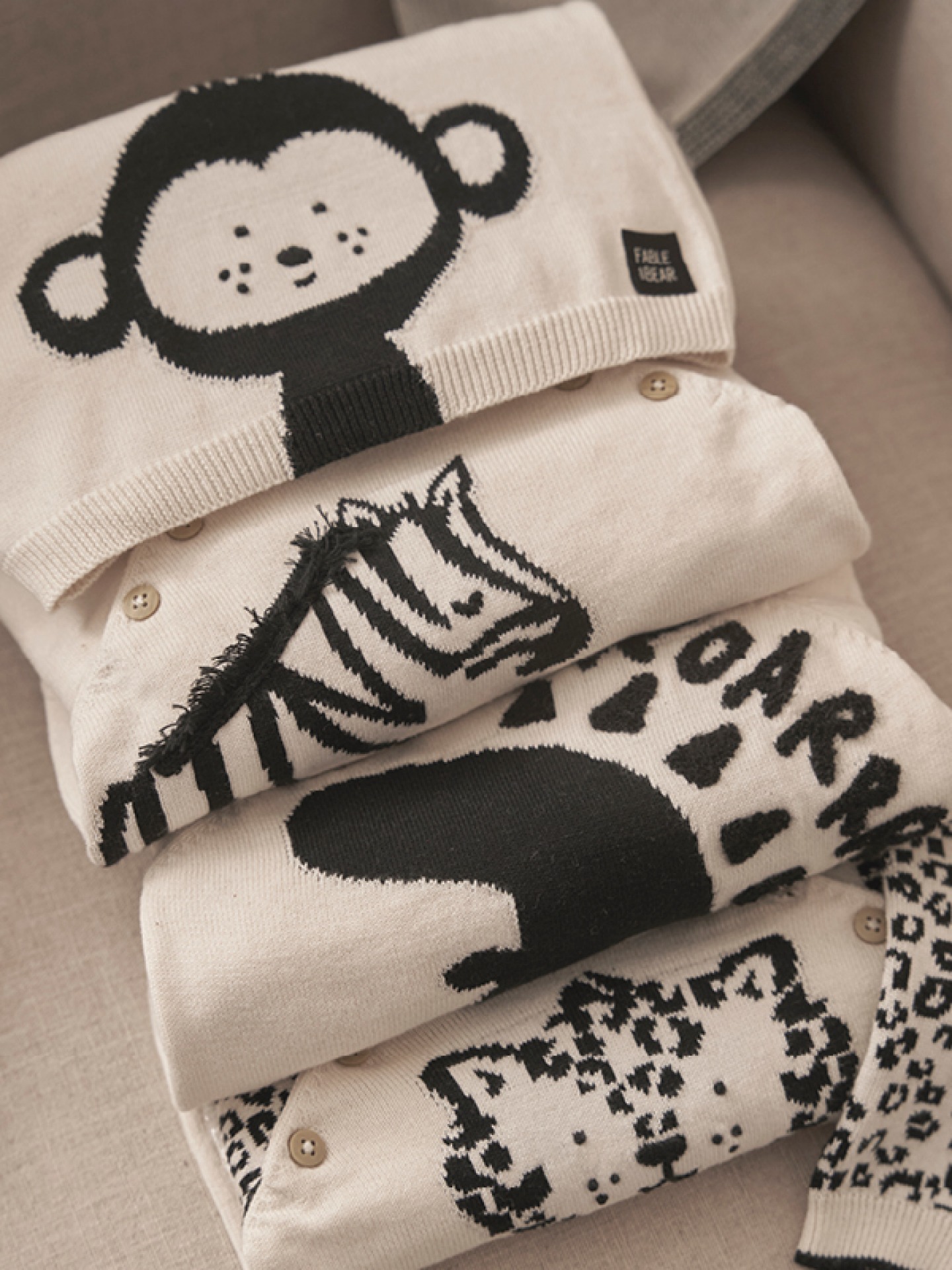 stack of cream knitted kids clothes with black animal prints