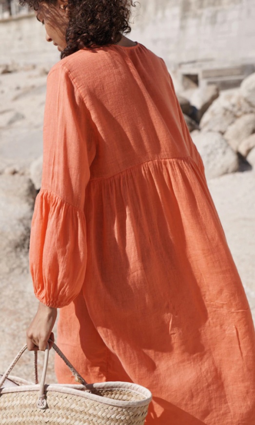 woman with beach bag wearing coral long sleeved dress