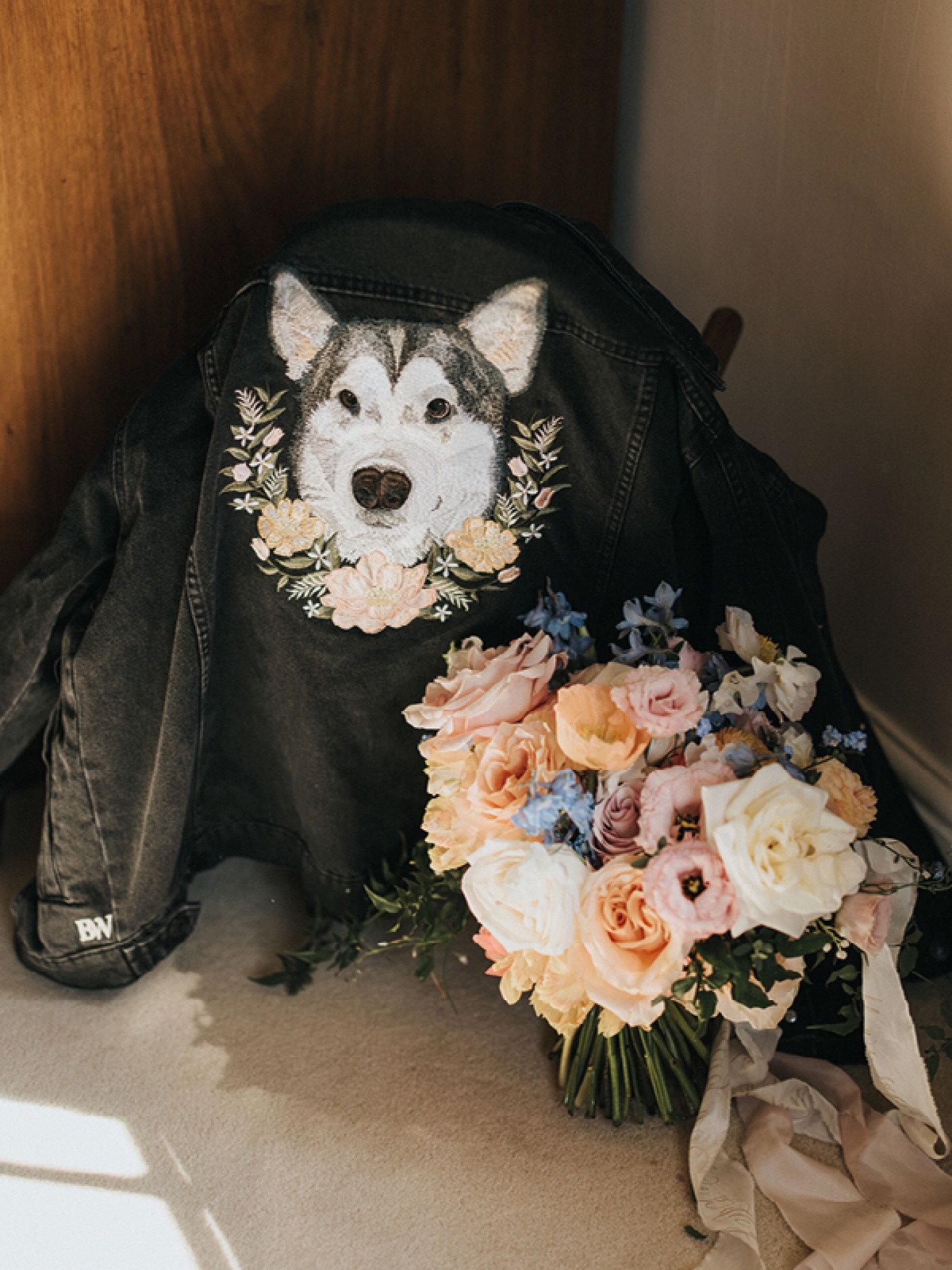 Dog and flowers embroidered on the back of a black denim jacket