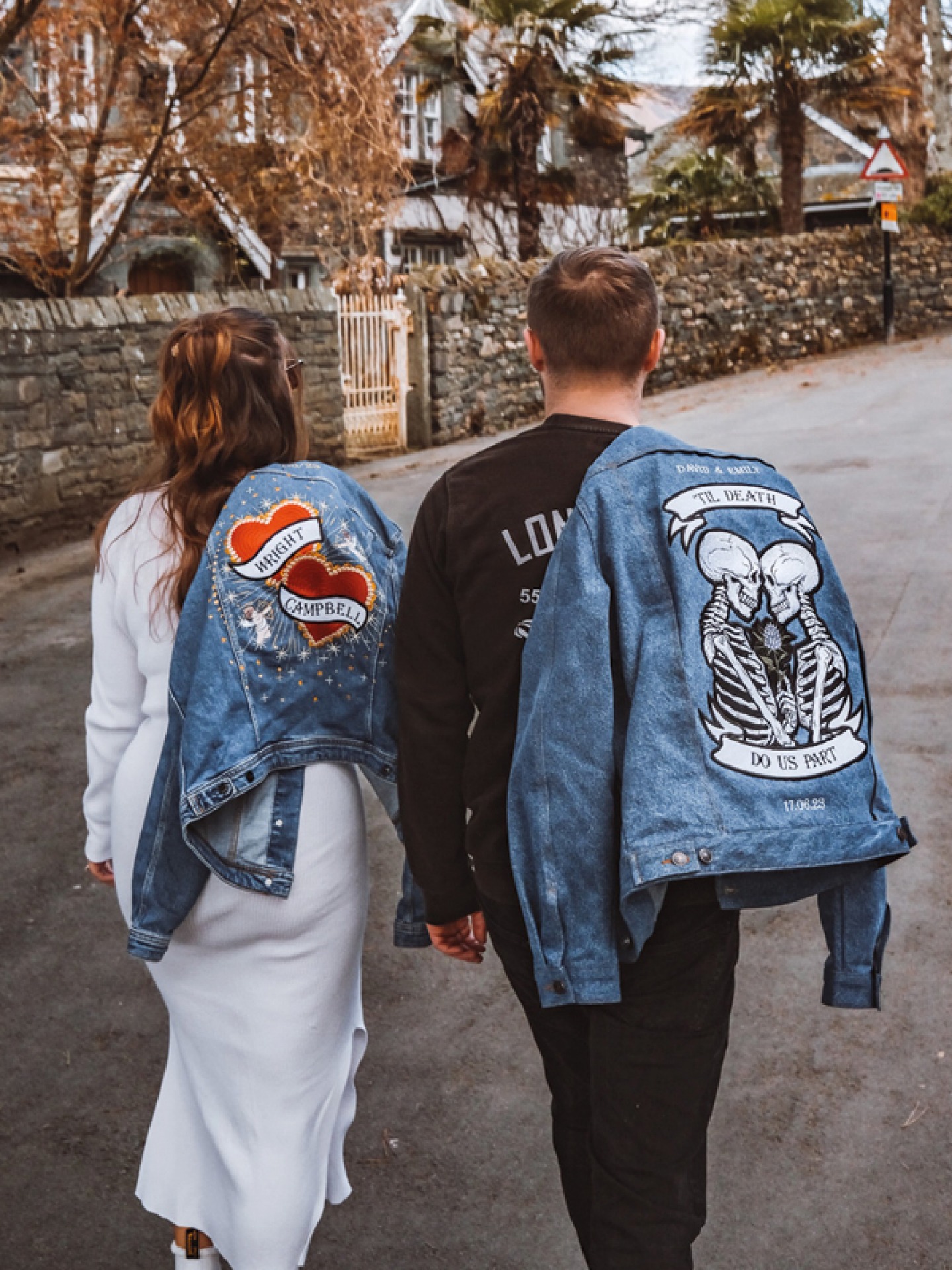 Couple walking up a street holding embroidered denim jackets