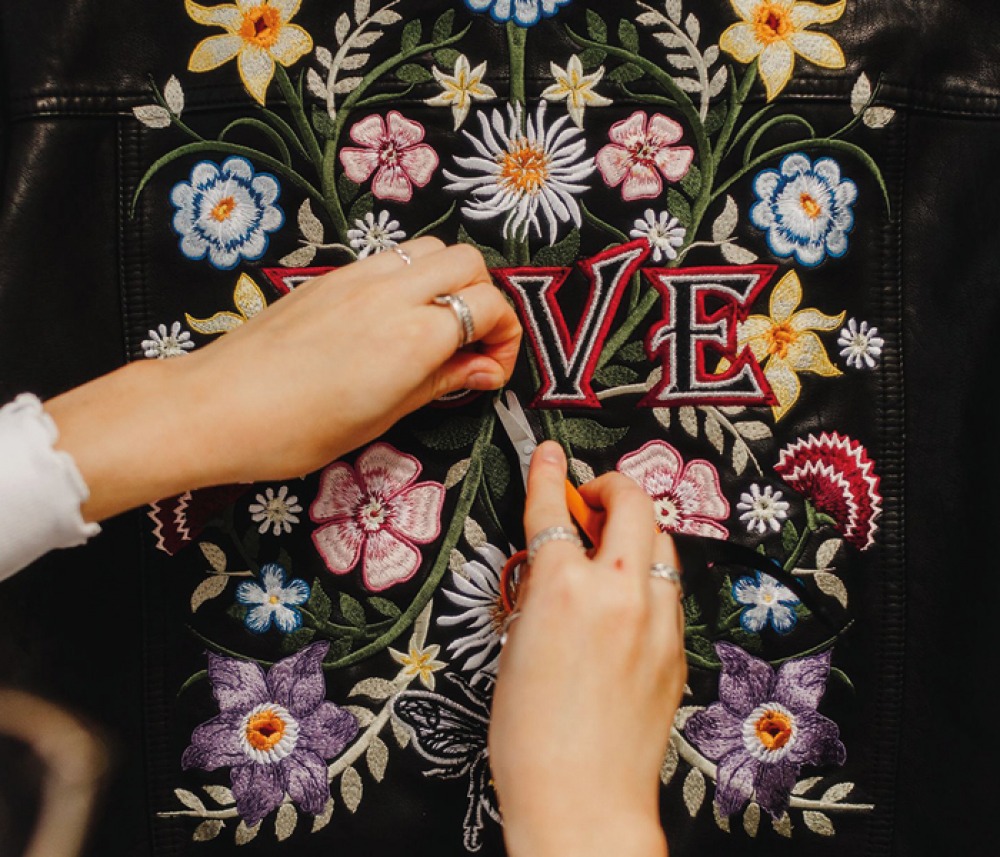 LOVE with a floral pattern being embroidered onto a black jacket