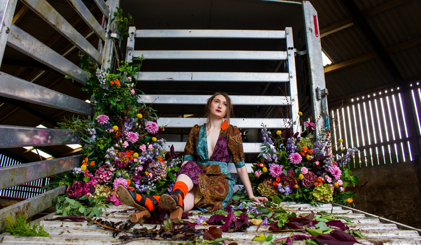 Model wearing Sarahs clothes sitting in a metal structure surrounded by flowers