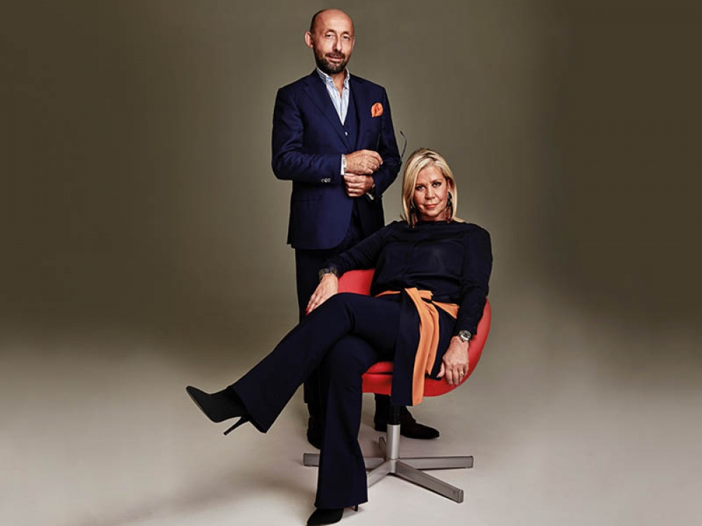 man standing and a women sat in a chair