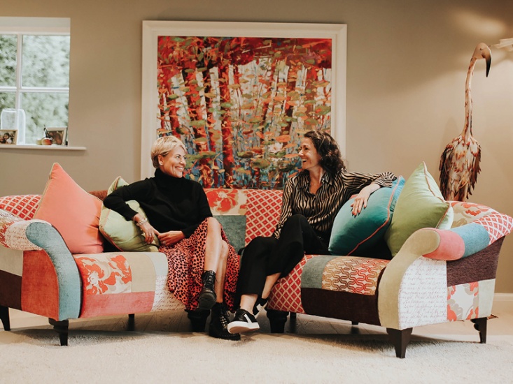 Heather Jackspon and Sam Simister sitting talking on a large patchwork sofa
