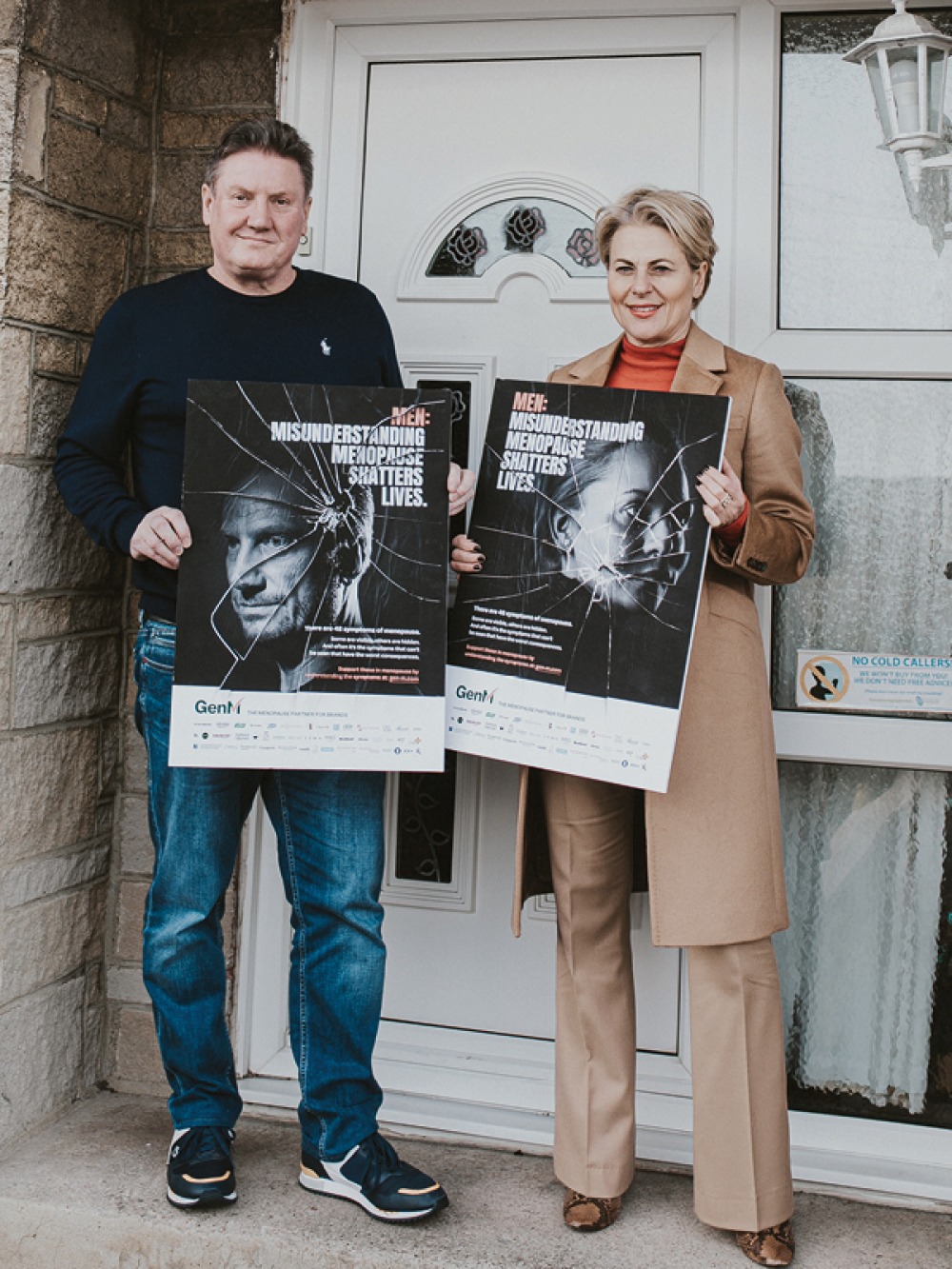 David Salmon and Heather Jackson standing at doorway holding Shattered Campaign boards