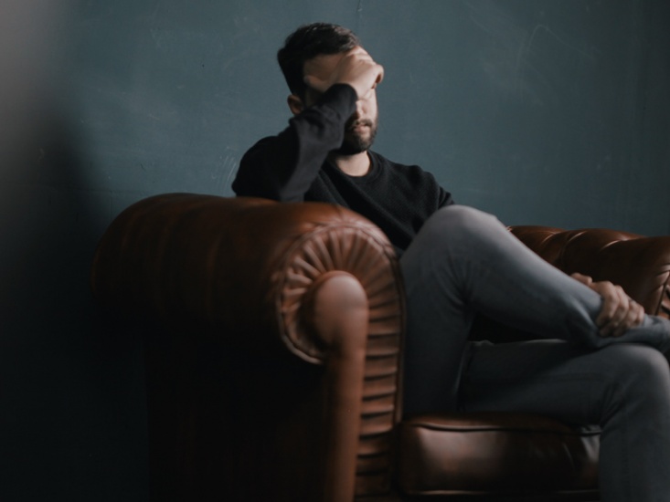 A man sitting in a chair with his head in his hand
