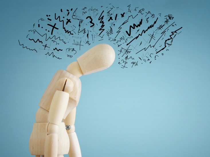 wooden mannequin hunched over with scribbles surrounding the head