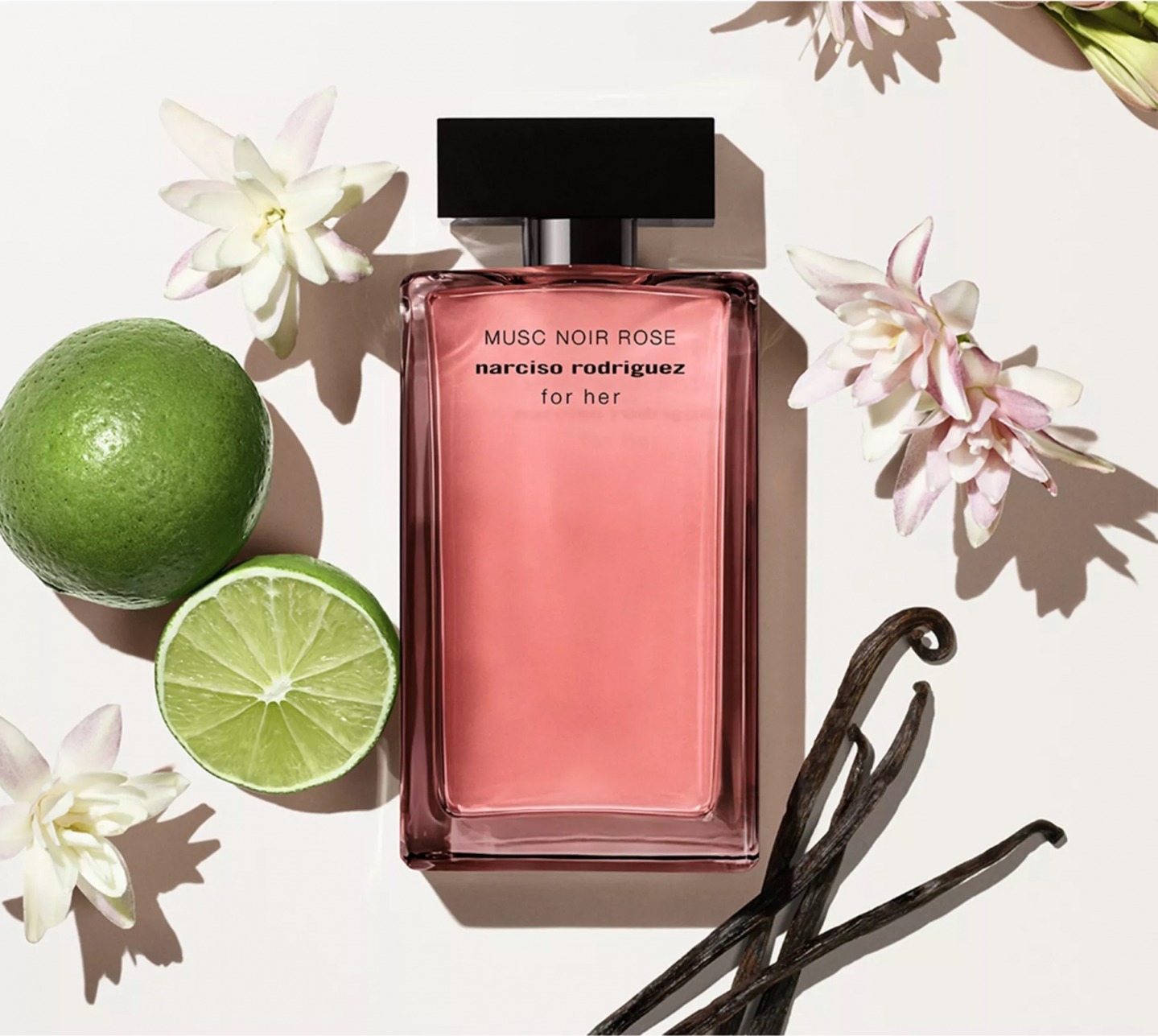perfume bottle pictured with limes, flowers and vanilla pods