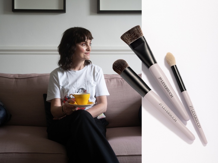 woman holding a yellow teacup and makeup brushes