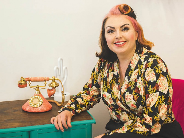 Woman posing, resting on a side board with a retro dial phone