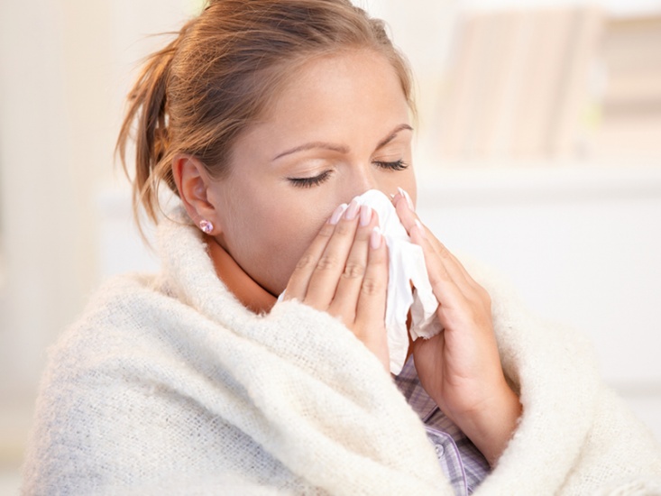 woman in dressing gown blowing nose with tissue
