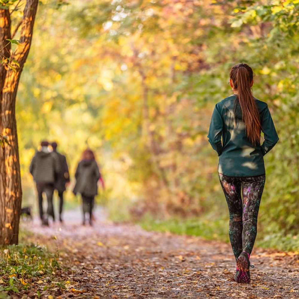 woman walking along leafy path