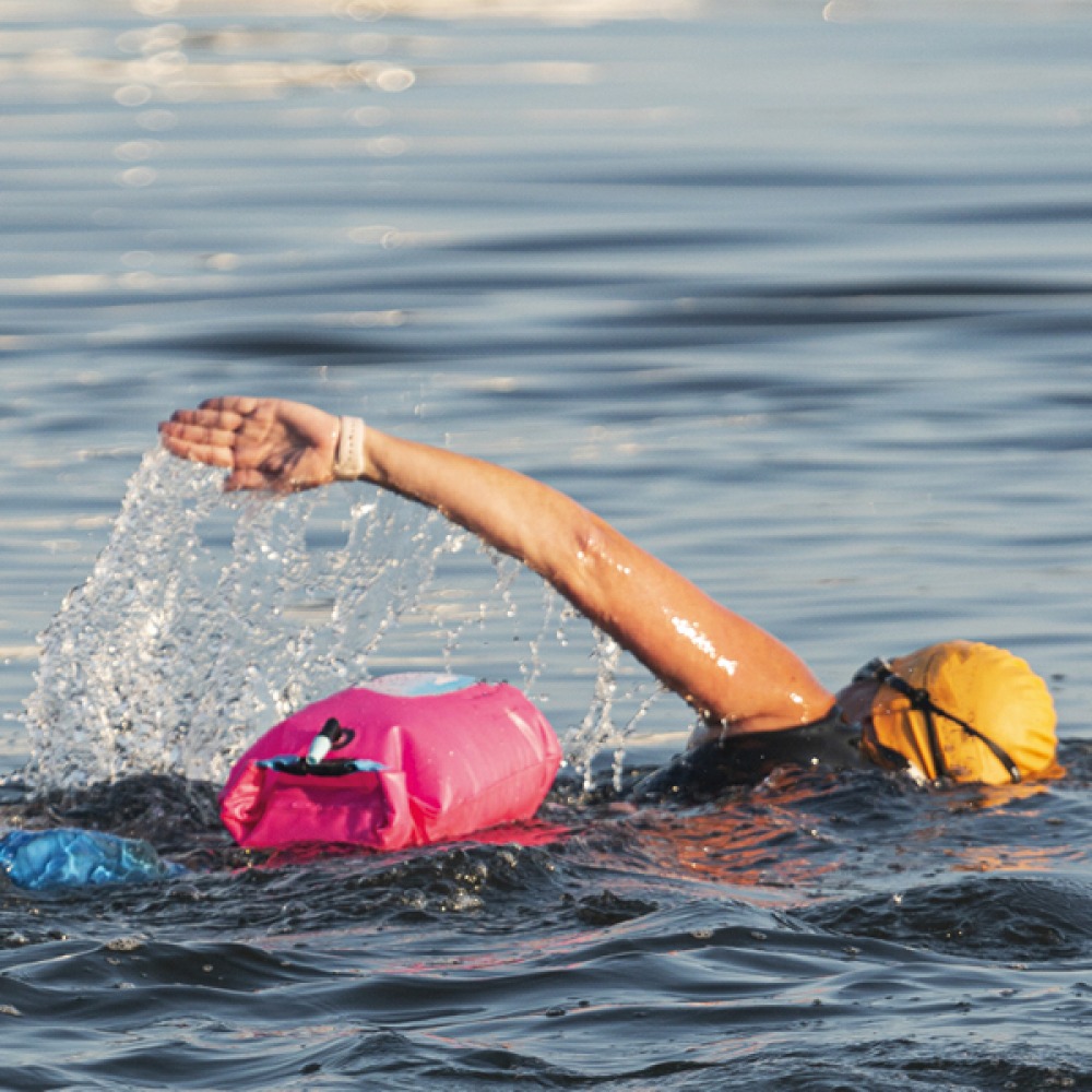 Woman wild swimming wearing yellow cap with pink Tow Float