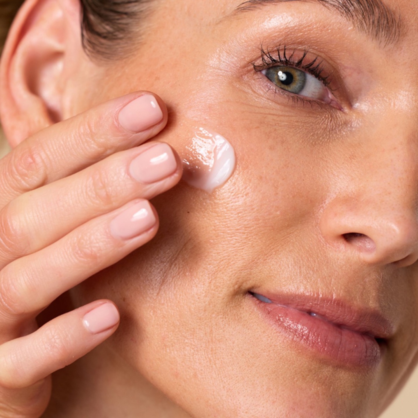 Model smoothing cream into cheeks