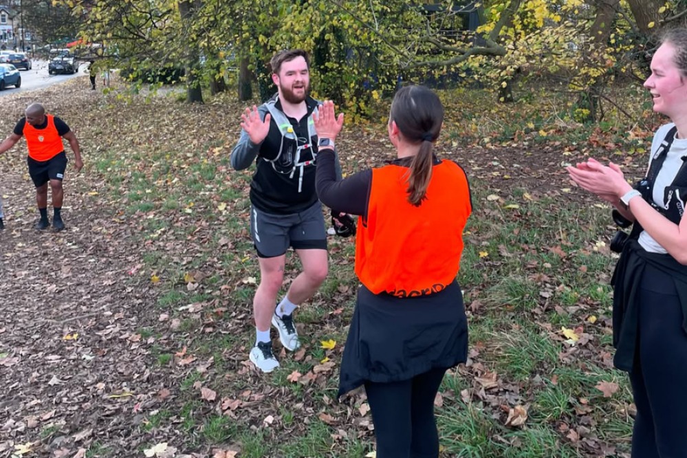 man running in autumn high-fiving a marshal