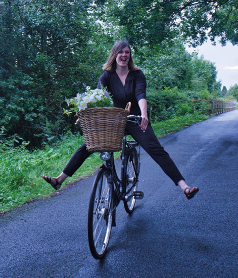 Eileen Hoey riding a bike with a basket of fresh flowers