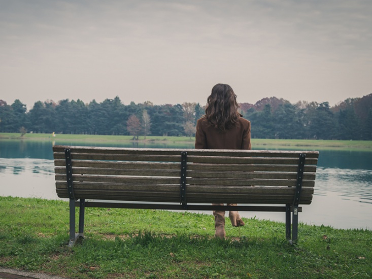 person sitting on a bench looking at a lake