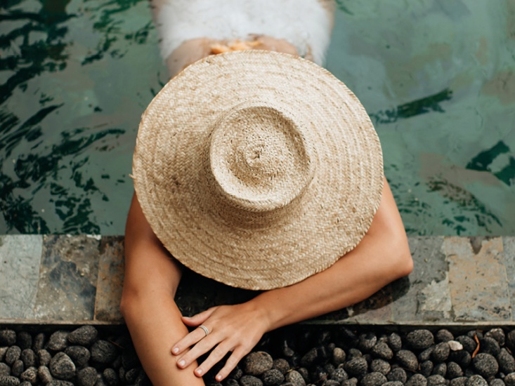 Woman wearing a sun hat lying in the pool