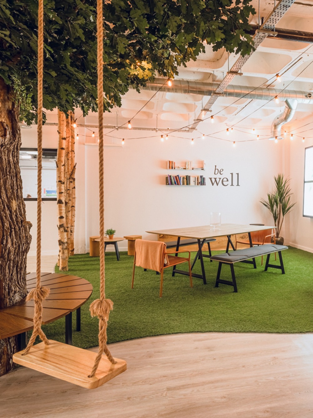 tree with a seat around it, a swing hanging looking over a greased seating area with table