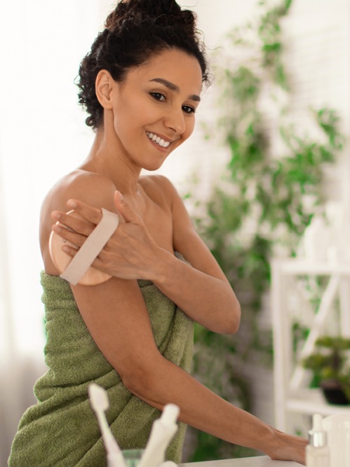woman wearing green towel dry brushing her arms