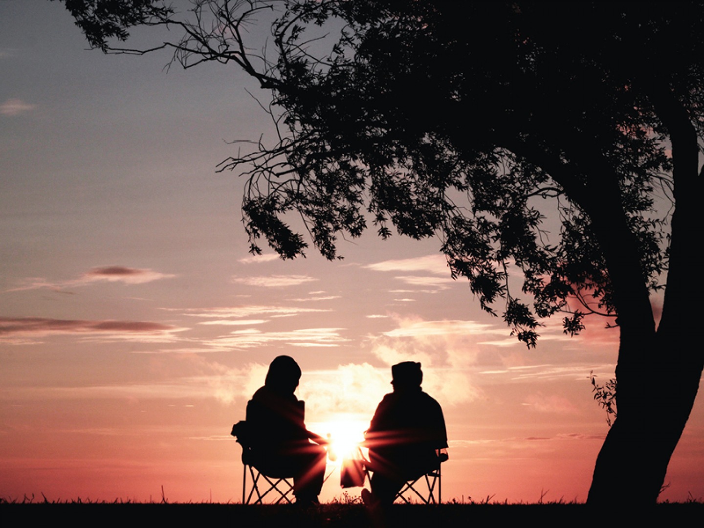 sunset over two people sitting down