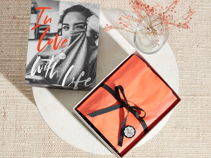 box wrapped in red tissue paper with a black bow