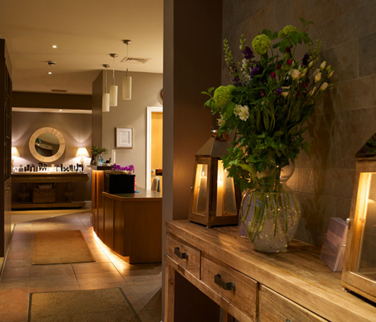 Hall way in a spa with candles and flowers on a side table