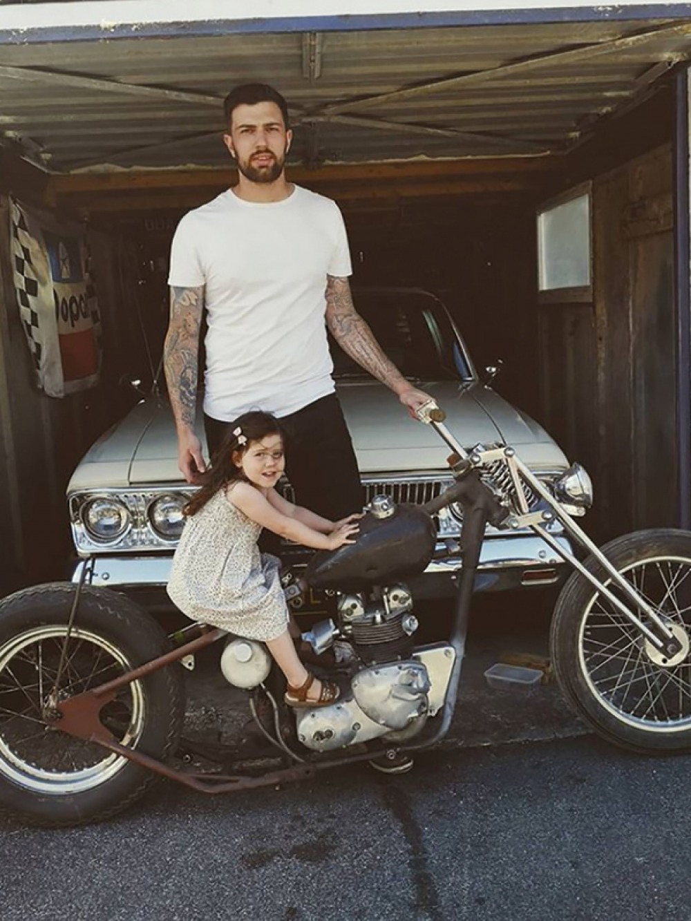 matt standing in garage way behind a child sitting on a motorbike