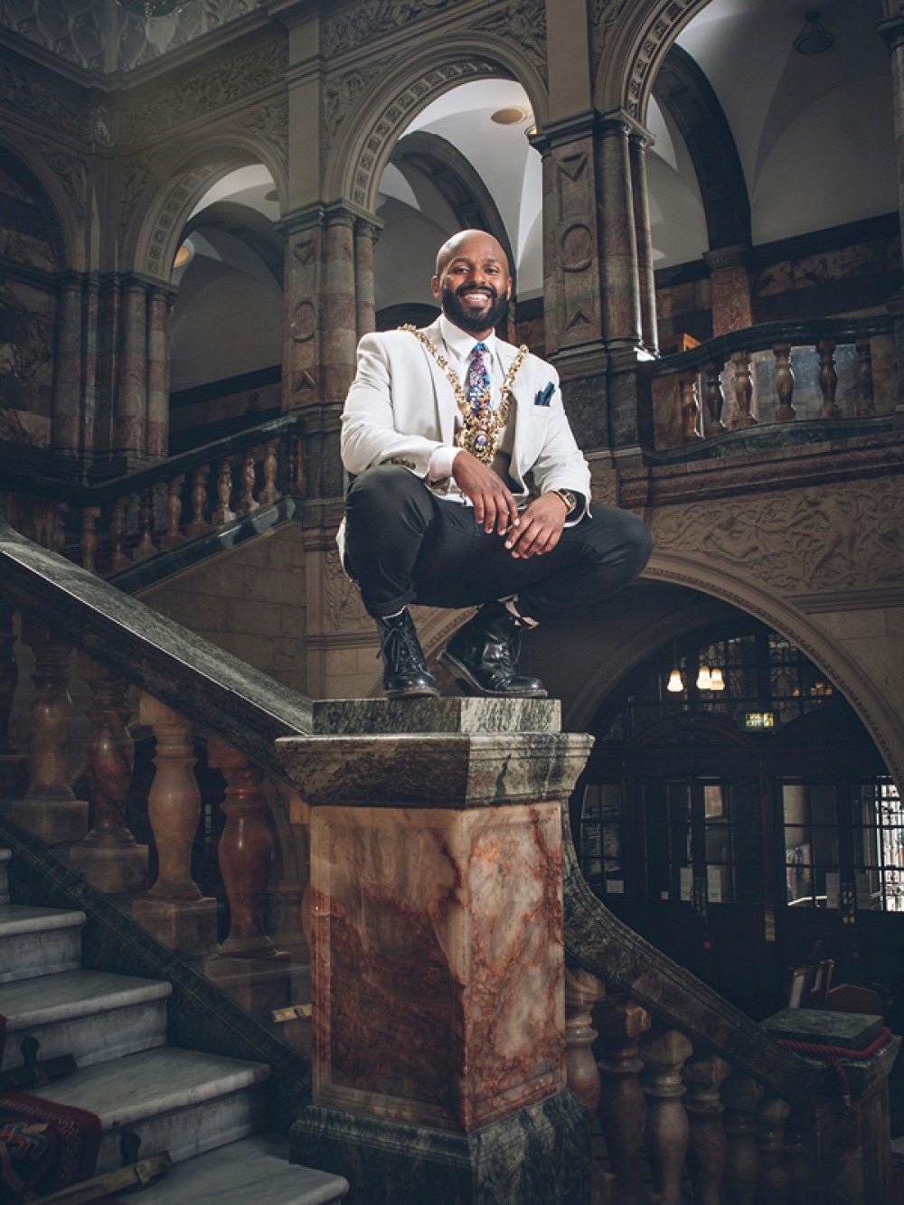 Magid Magid crouched down on a marble column staircase