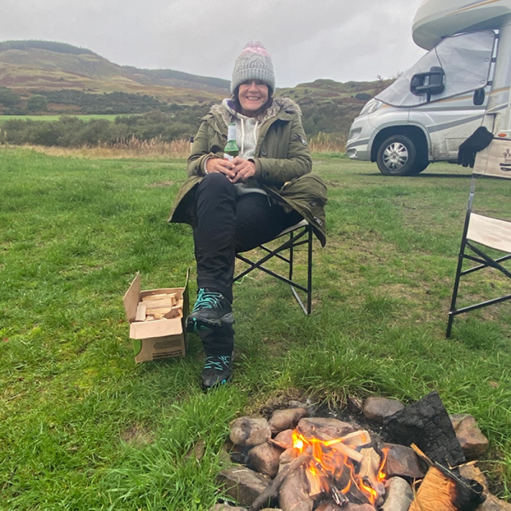 Siobhan sitting having a beer around a camp fire