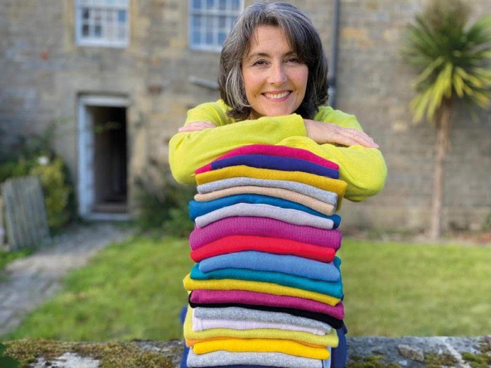 women standing over a pile of jumpers smiling