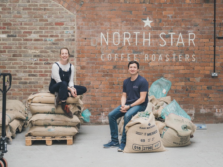 2 people sat on bags of coffee beans