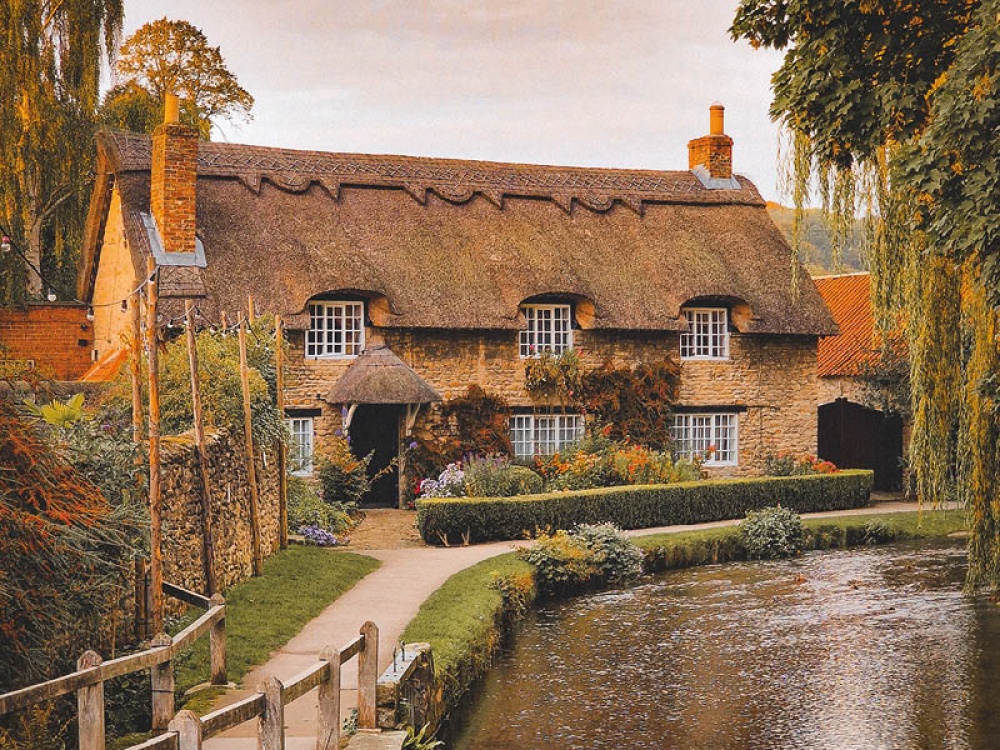 Idyllic thatched cottage with a river running past the front