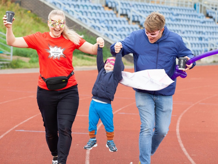 small child pretending to be a super hero next to their parents