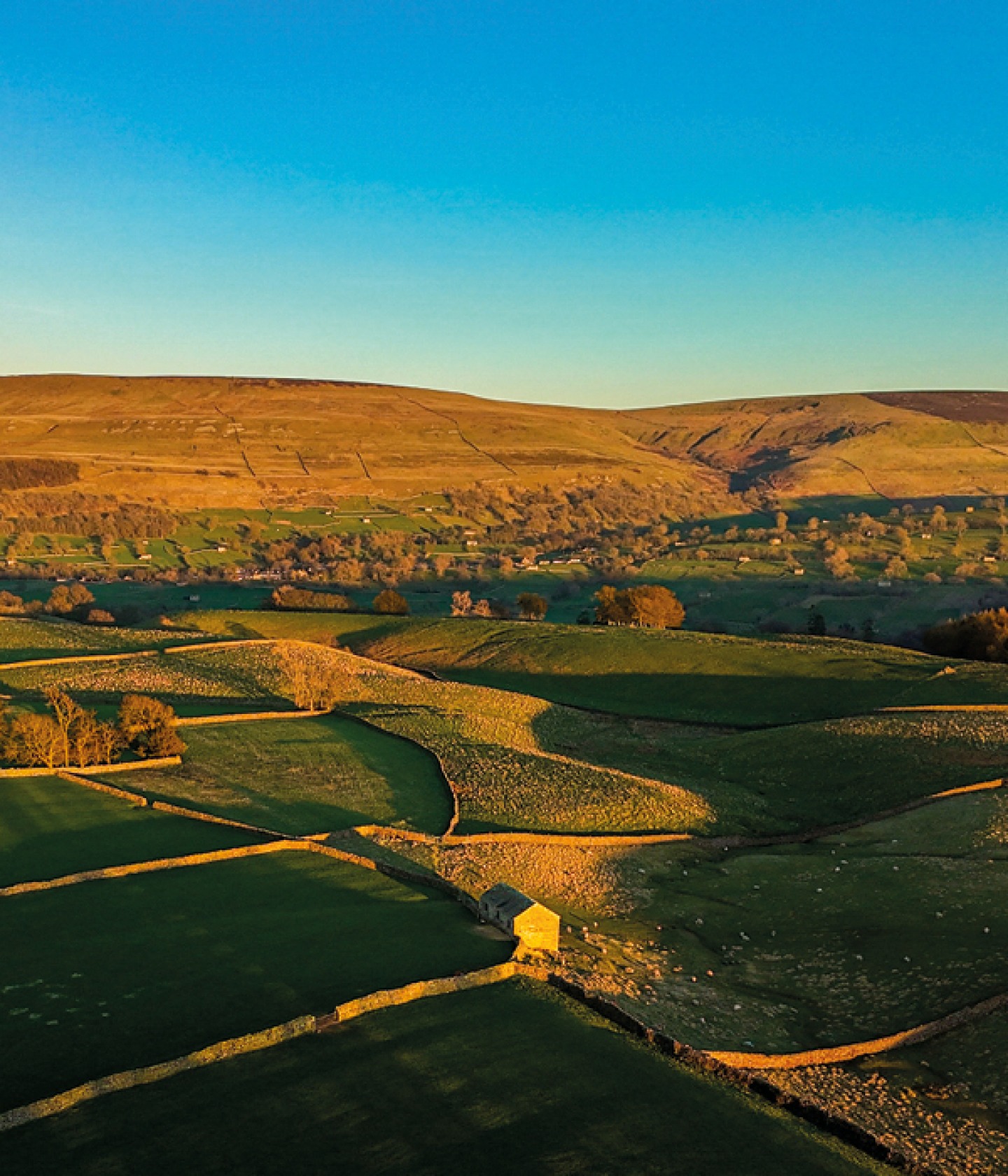 green farmed fields with stone buildings at sunset