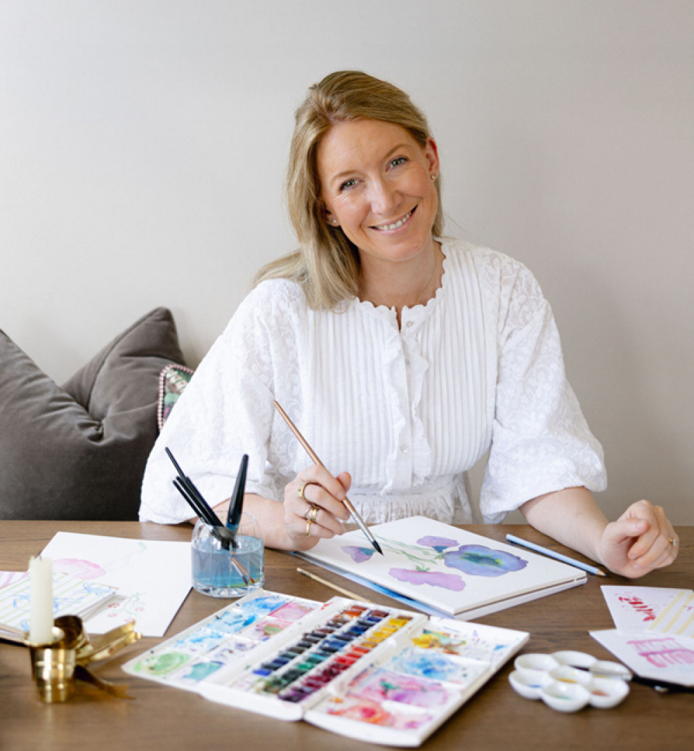 lady painting purple watercolour flowers in a sketchbook
