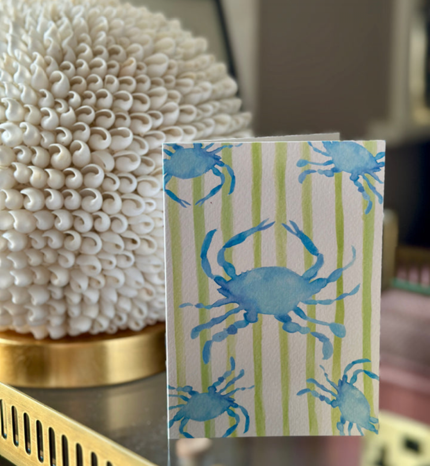 A watercolour notecard which has lime green stripes and 5 blue crabs
