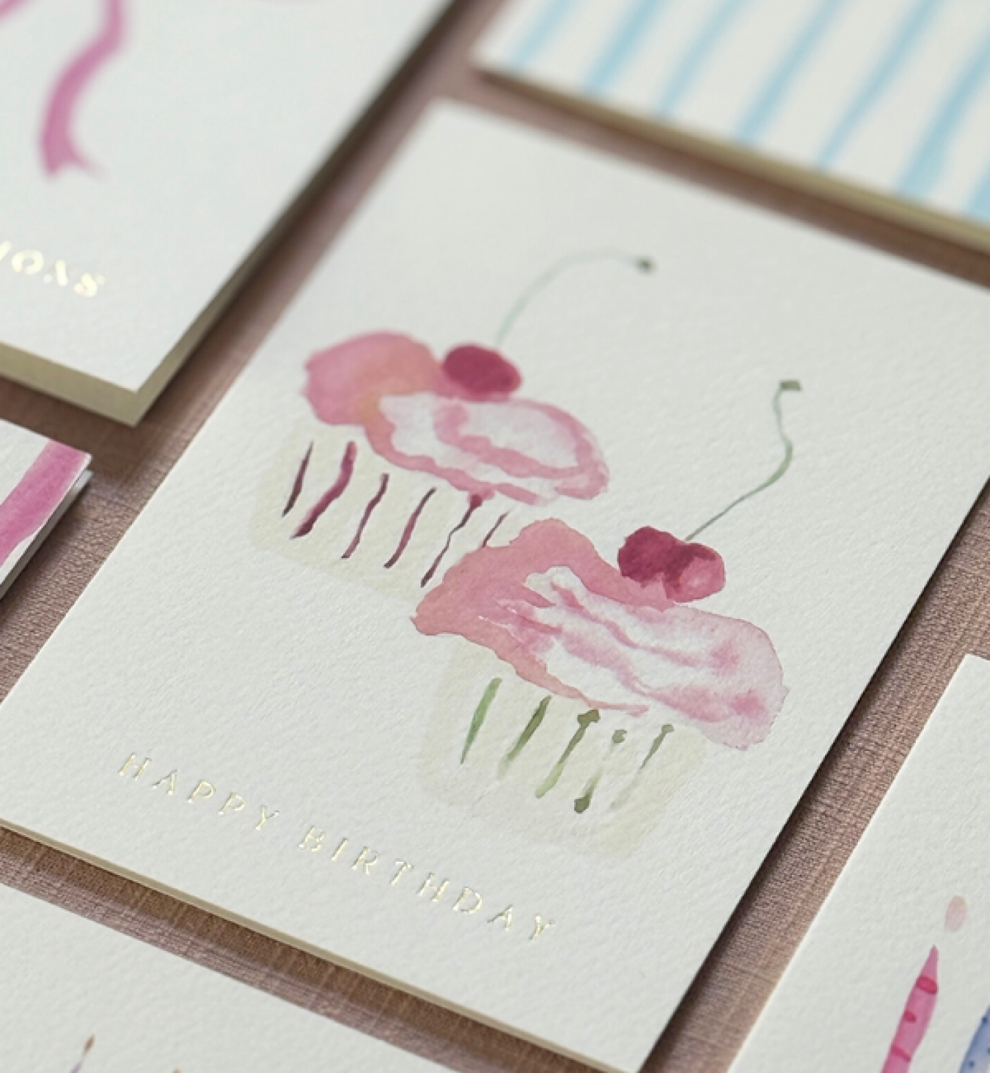 close up of a watercolour cupcake card with gold foil 'Happy Birthday'