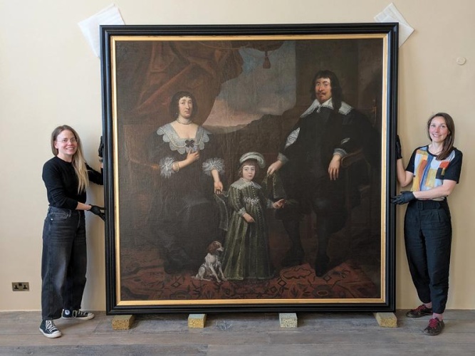 two women holding a large painting