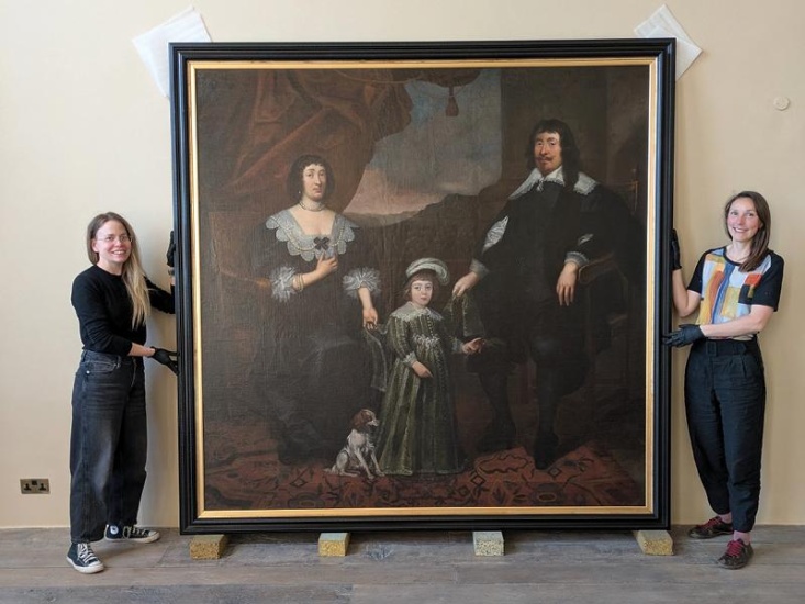 two women holding a large painting