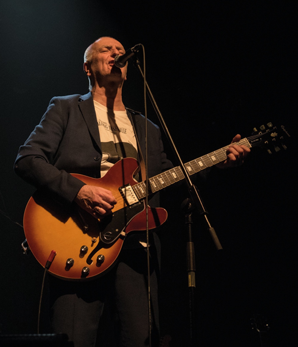 Trevor Sewell on stage playing his guitar and singing