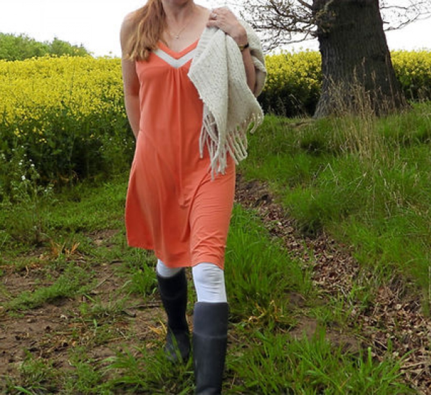 model walking outdoor wearing orange nightgown white leggings and wellies