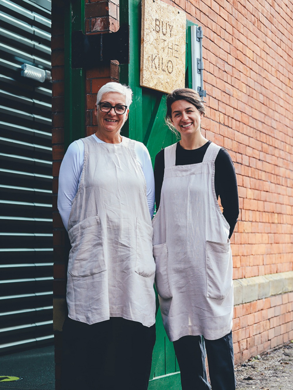 2 ladies standing in front of brick building with green shutters