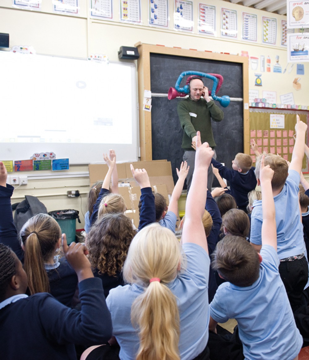children in a class room with their hands up