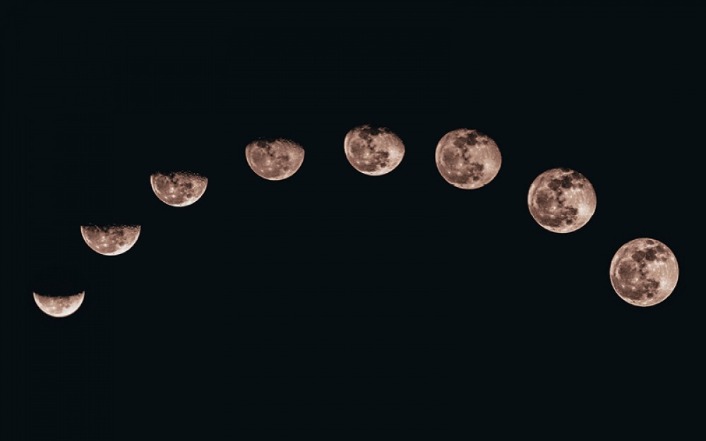 eight different moons on black background